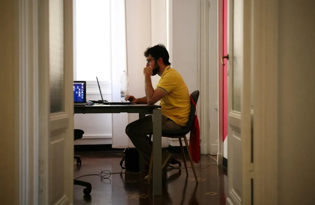 A man focused on his laptop at a desk, highlighting key aspects of proposal management software for improved operations.